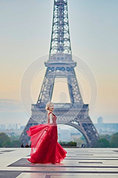 Woman in long red dress dancing near the Eiffel tower in Paris, France