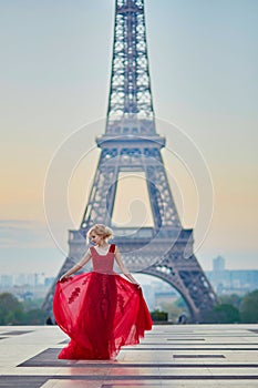 Woman in long red dress dancing near the Eiffel tower in Paris, France