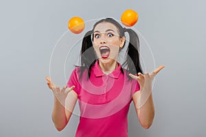 Woman with long straight hair, holding two oranges, looking up