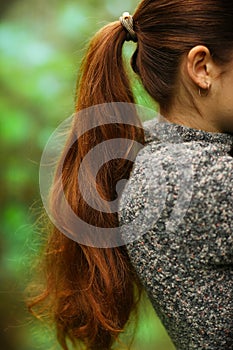 woman with long thick brown hair pony tale close up photo on green summer garden background photo