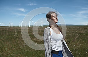 Woman with long tousled hair next to the wind turbine with the wind blowing