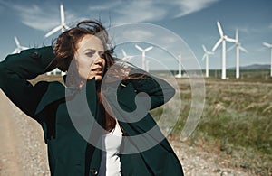 Woman with long tousled hair next to the wind turbines