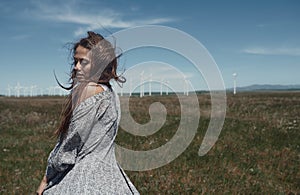 Woman with long tousled hair next to the wind turbines
