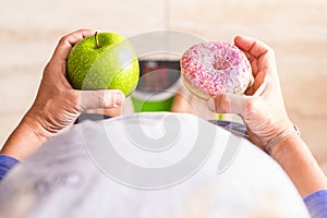 Woman look at donut and apple to select her nutrition lifestyle - she`s on a weight scale