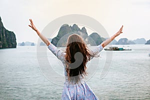 Woman look on HALONG bay in Vietnam and rise hands. UNESCO World Heritage Site.