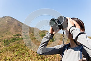 Woman look though binocular when going hiking