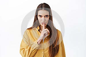 Woman look threatening and shushing, telling to be quiet, keep secret unless, making taboo gesture and staring serious