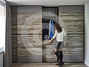 Woman look into an wardrobe with clothes and opens drawer