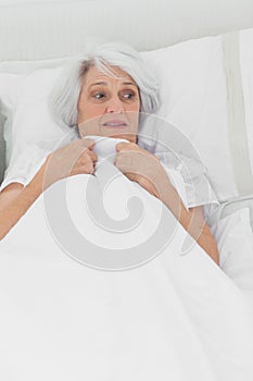 Woman looking afraid in her bed