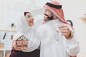 Woman looking at arab man while holding house.