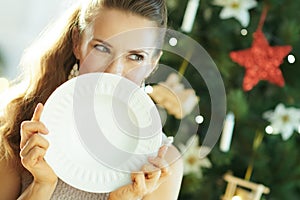 Woman looking aside while hiding behind serving dinner plate