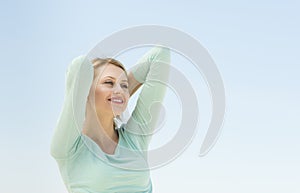 Woman Looking Away With Arms Raised Against Clear Sky