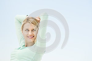 Woman Looking Away With Arms Raised Against Clear Sky