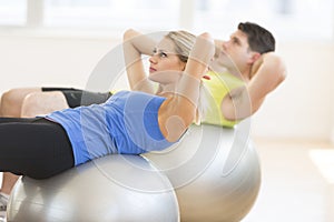 Woman Looking Away While Exercising On Fitness Ball At Gym