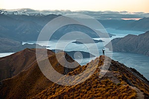 A woman looking at the beautiful landscape of the mountains and Lake Wanaka. Roys Peak Track, South Island, New Zealand. I