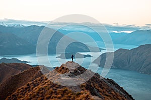 A woman looking at the beautiful landscape of the mountains and Lake Wanaka. Roys Peak Track, South Island, New Zealand. I