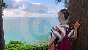 Woman is looking at the Black Sea, green trees and blue cloudy sky