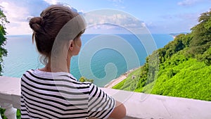 Woman is looking at the Black Sea, green trees and blue cloudy sky