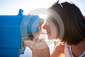 Woman looking through a blue iron telescope