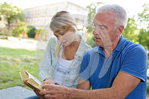 woman looking at book with father