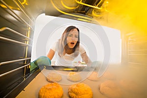 Woman Looking At Burnt Cookies In Oven