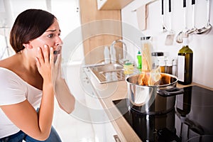 Woman Looking At Burnt Food In Cooking Pot