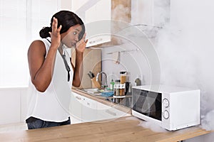 Woman Looking At Burnt Pizza In Microwave Oven
