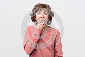 Woman looking at camera covering mouth with hands in disbelief