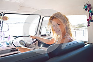 Woman looking at camera while driving a camper van at beach