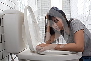 Woman looking at camera drunk hangover puke in toilet bowl. Female have abdominal pain, nausea, dizziness, nausea, vomit due to
