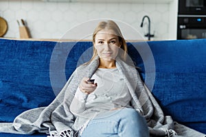 Woman looking at camera holding remote control watch TV