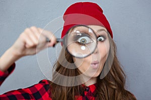 Woman looking at the camera through magnifying glass