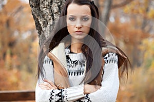 Woman looking at camera near tree in autmn park