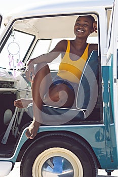 Woman looking at camera while sitting in a camper van at beach