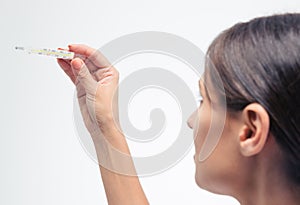 Woman looking at clinical thermometer