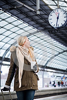 Woman looking at clock in train station as her train has a delay