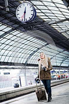 Woman looking at clock in train station as her train has a delay