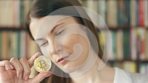 Woman looking at cryptocurrency bitcoin. Shiny virtual money of online trade. Focus on bitcoin