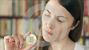 Woman looking at cryptocurrency bitcoin. Shiny virtual money of online trade. Focus on bitcoin