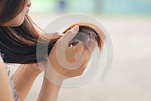 Woman looking at damaged splitting ends of hair, Haircare concept