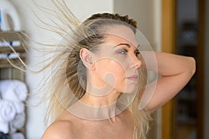 Woman looking at the dark roots if her dyed blond hair