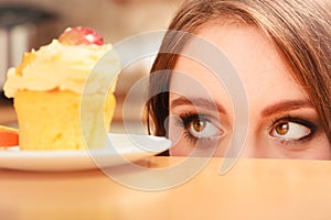 Woman looking at delicious sweet cake. Gluttony.