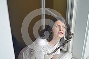 Woman looking delighted out of the window into the sky