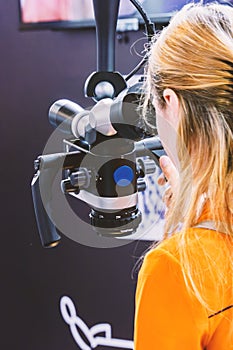 Woman looking into a dental microscope