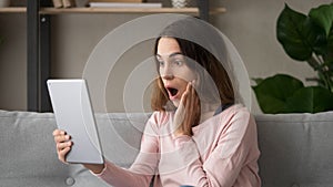 Woman looking at digital tablet screen feels shocked about news