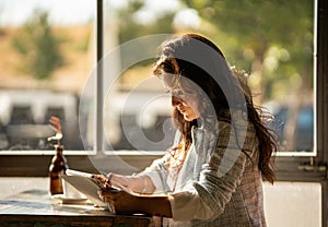 Woman looking at digital tablet screen while sitting in a coffee shop next to the window