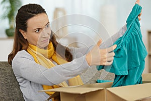 Woman looking with disdain at top delivered by courrier photo