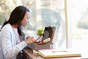 Woman Looking At Document In Keepsake Box On Desk