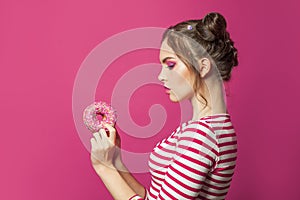 Woman looking at donut on vivid pink background, diet concept