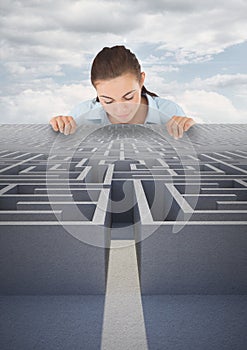 Woman looking down to a maze against blue sky